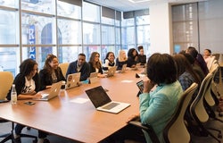 a group of people sat around a workplace meeting table in discussion