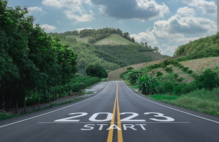 Image of a road leading to a mountainous landscape with 2023 written on the road