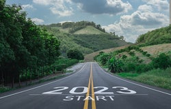 Image of a road leading to a mountainous landscape with 2023 written on the road