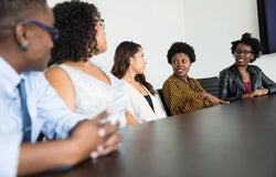 a group of businesswomen speaking at a table