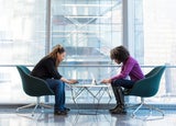 two women at a workplace sitting across a desk from each other